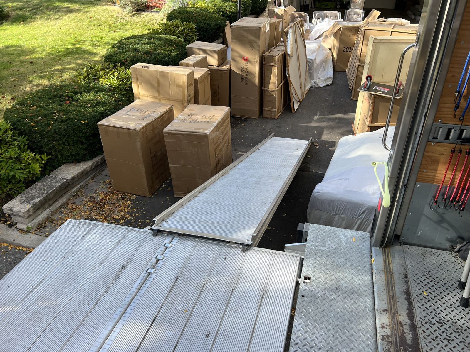 Crated furniture boxes staged on a driveway beside the moving truck ramp