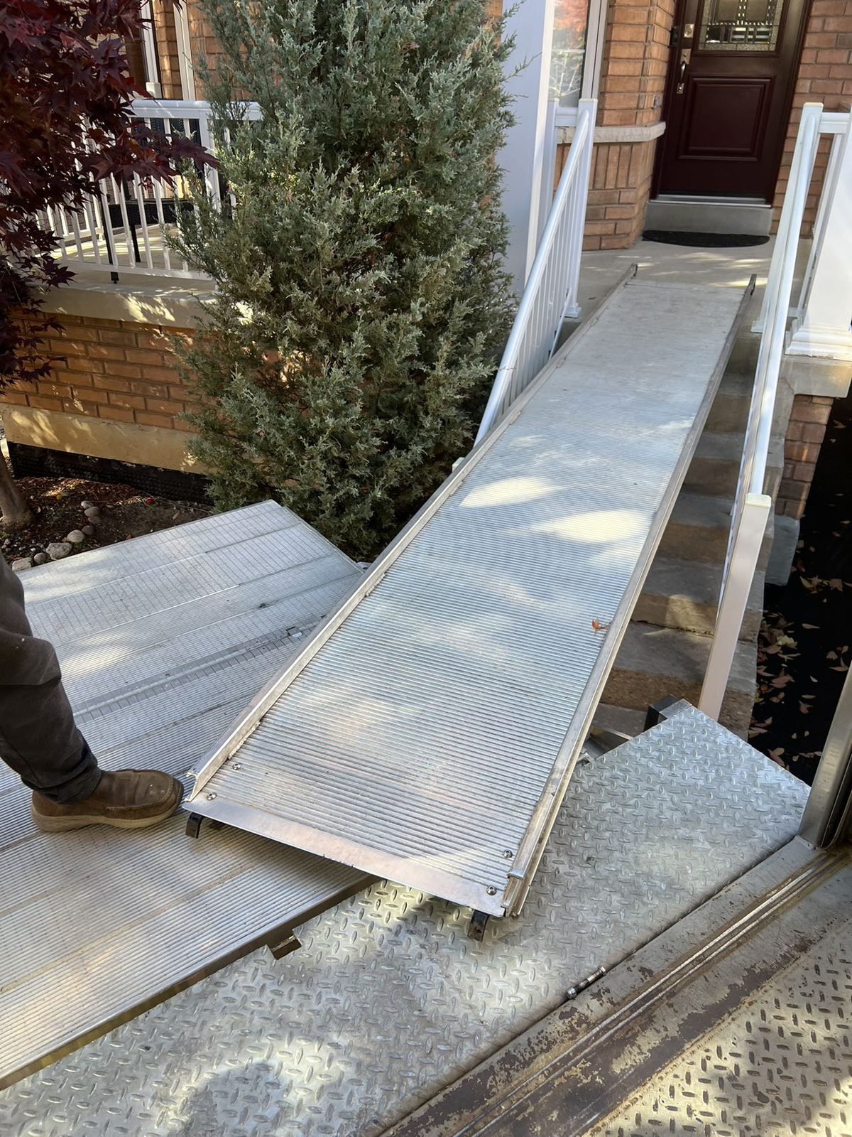 Close view of an aluminium moving ramp set from the truck deck over concrete front steps