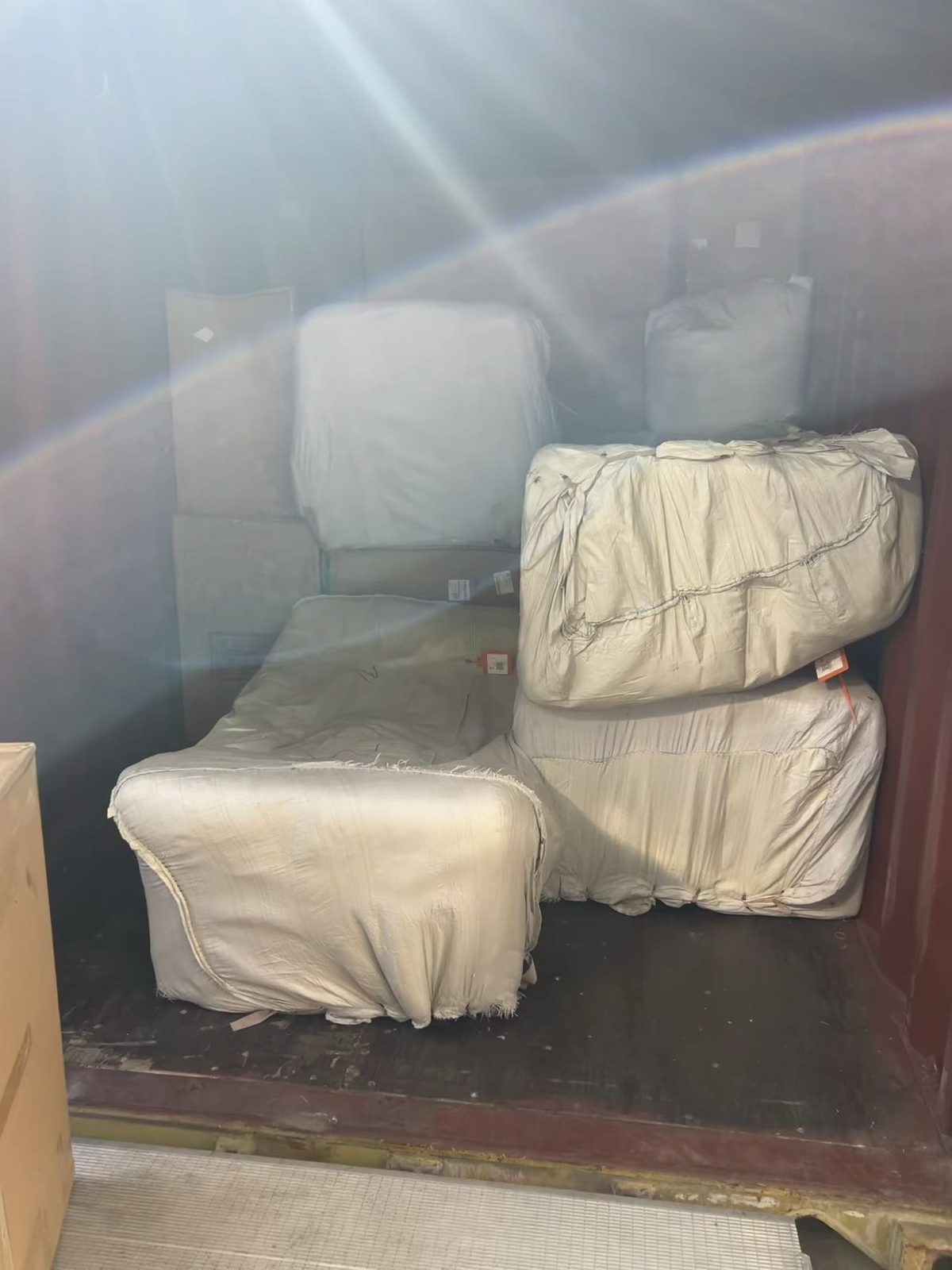 Sofa and armchairs fully wrapped in protective covers and loaded into a shipping container