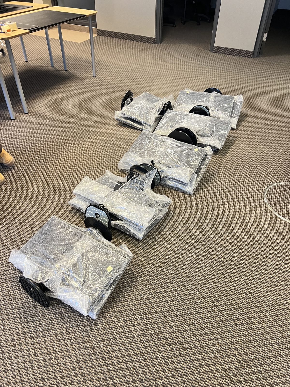 Office chairs individually wrapped in plastic film and lined up before an office move