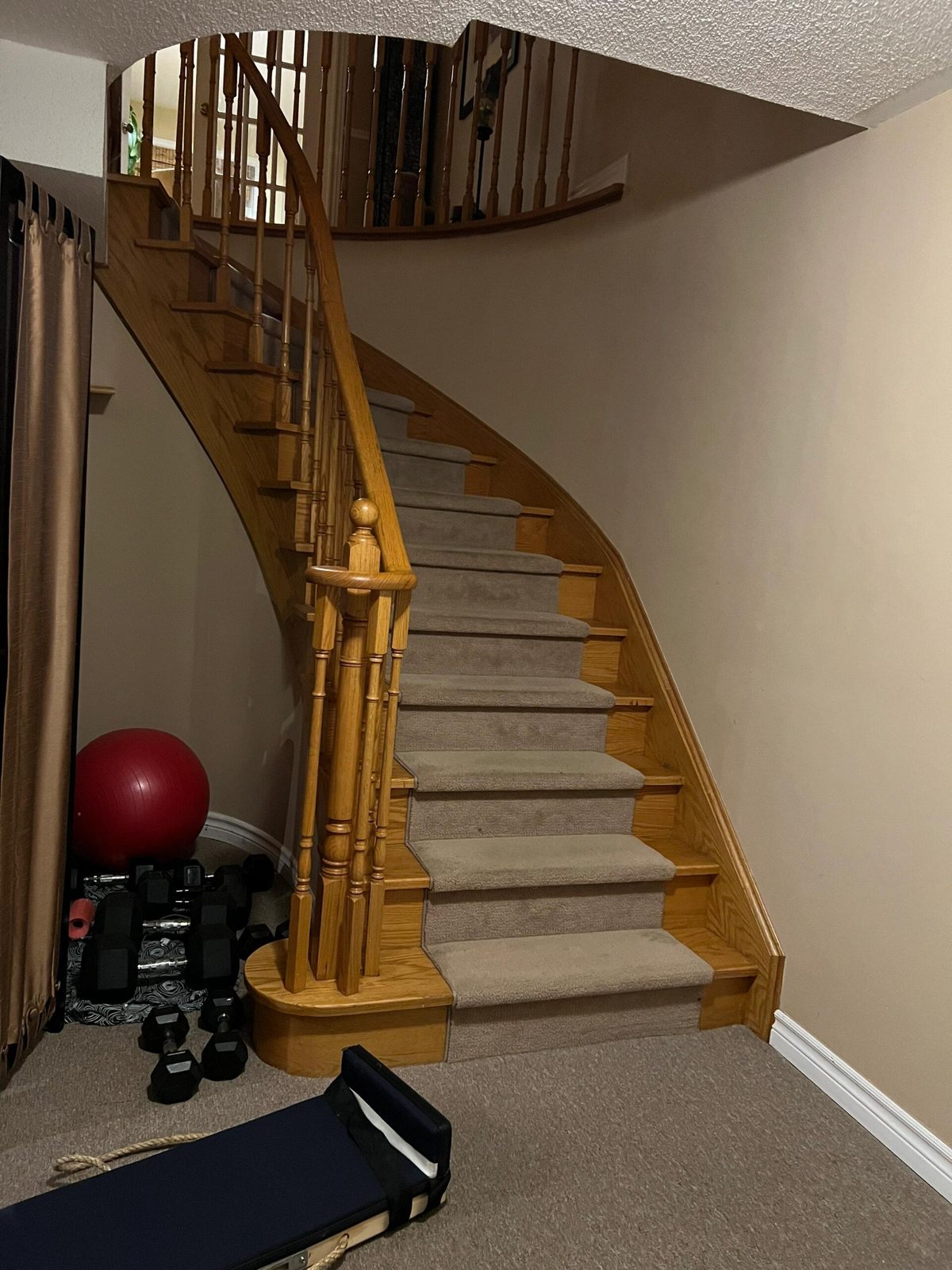 Curved carpeted basement staircase with a turn, too narrow for a piano dolly